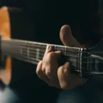 Ruke glazbenika na žicama akustične gitare