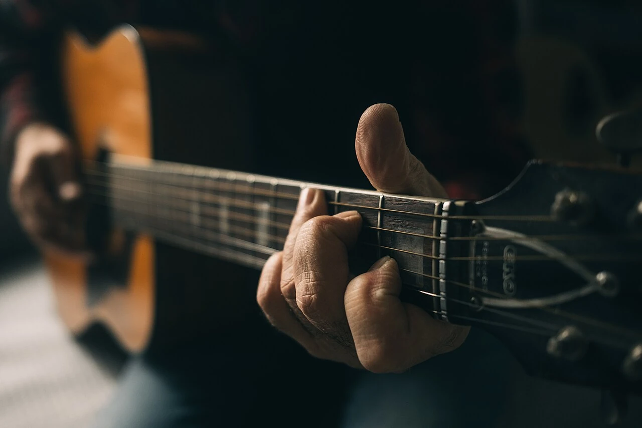 Ruke glazbenika na žicama akustične gitare
